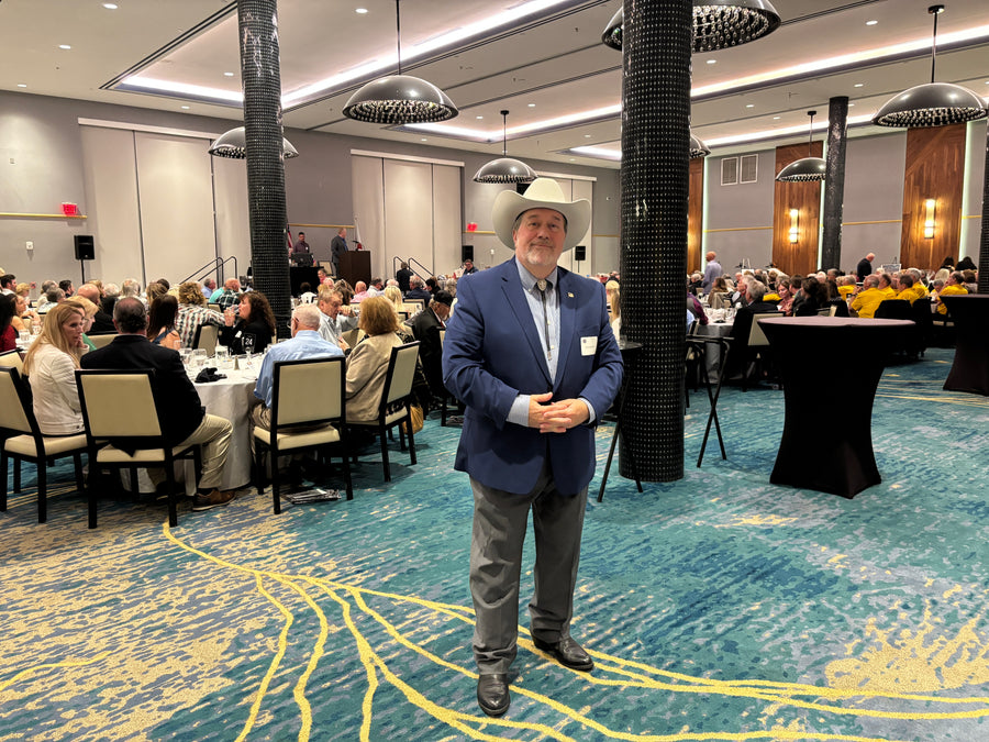 Eric D. Alexander speaking at a podium before a full ballroom
